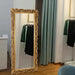 Decorative gold-framed mirror in a room with clothes and curtains.