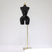Black mannequin torso on a gold stand against a white background