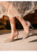 Elegant high-heeled shoes with decorative elements worn with a sparkling dress.