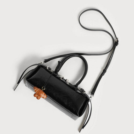 Black handbag with a wooden handle on a light gray background