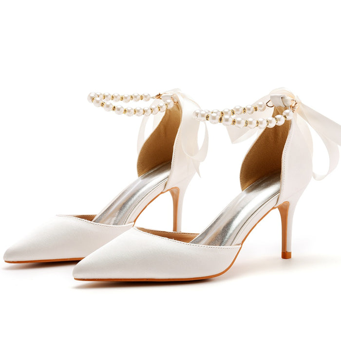 White high-heeled shoes with pearl anklets on a white background