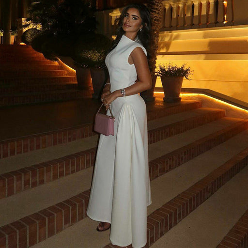 Woman in a white dress standing on a staircase with decorative plants and warm lighting.