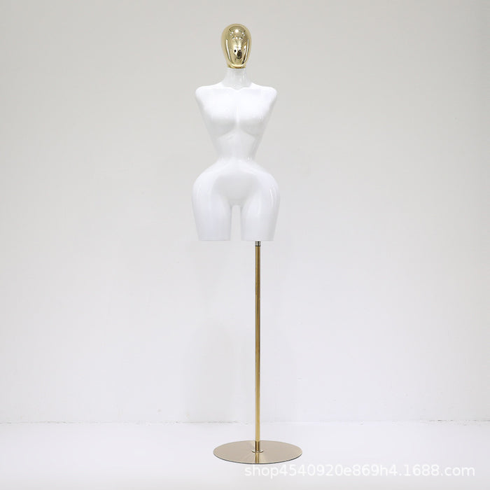 White mannequin torso on a gold stand against a white background
