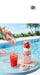Portable blender with strawberries being used to make a smoothie by a poolside.