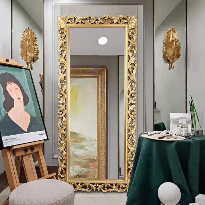 Decorative gold-framed mirror in a room with a table and artwork.