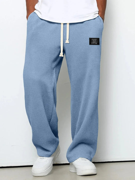 Blue textured sweatpants with a white label on a plain background
