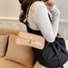 Person holding a beige handbag with a gold clasp on a couch.