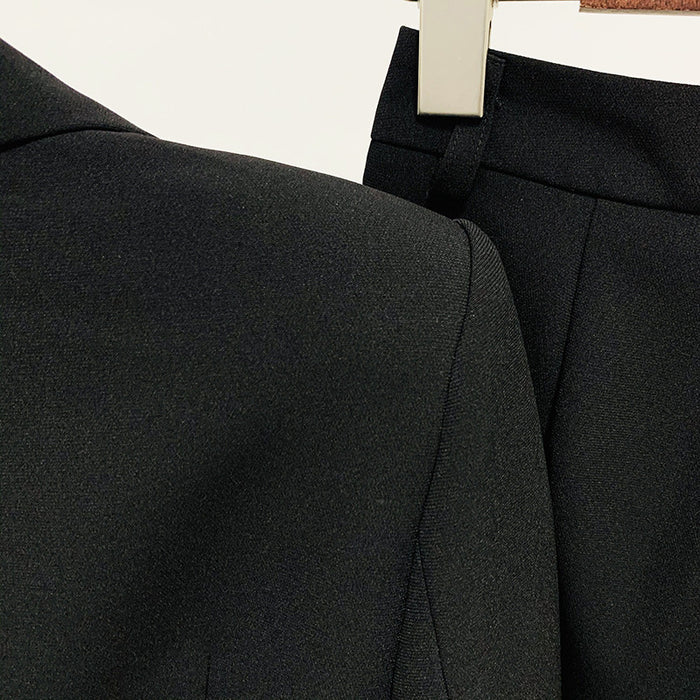 Close-up of a black suit jacket and pants on a hanger against a white background