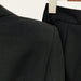 Close-up of a black suit jacket and pants on a hanger against a white background