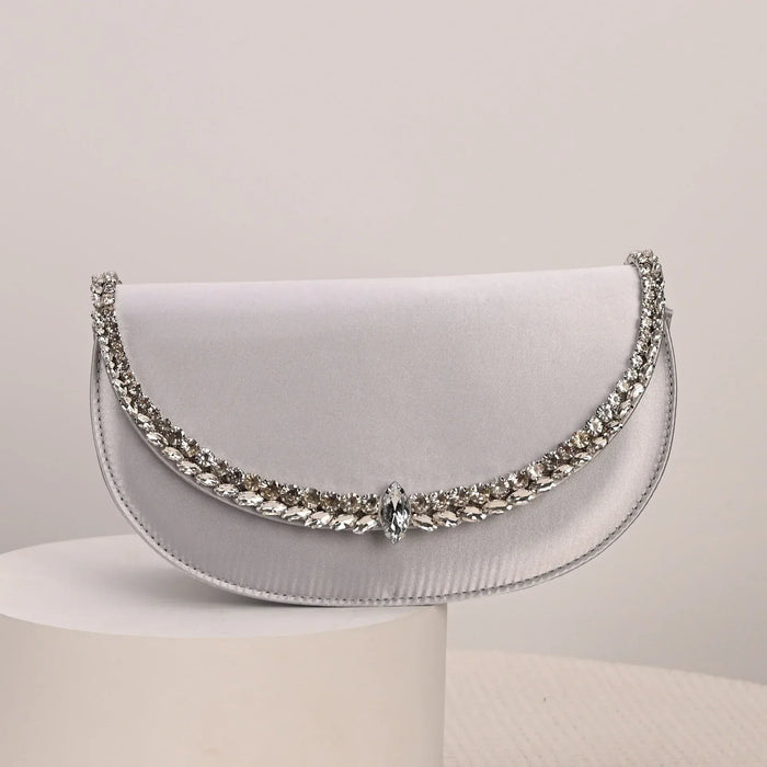 Silver clutch bag with gemstone embellishments on a light gray background