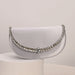 Silver clutch bag with gemstone embellishments on a light gray background