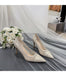 Pair of silver high-heeled shoes with a bouquet of white roses on a draped fabric background