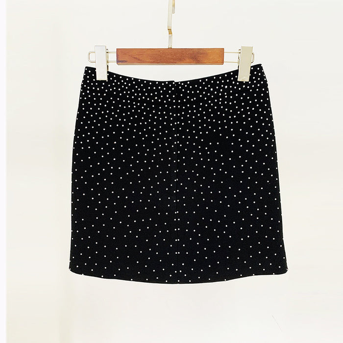 Black polka dot skirt on a wooden hanger against a white background
