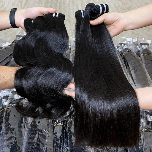 Two bundles of hair, one wavy and one straight, held by hands against a blurred background.