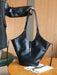 Black leather handbag on a wooden table with a blurred background