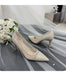 Pair of glittery high-heeled shoes on a tulle fabric with white roses.