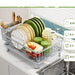 Dish drying rack with plates, bowls, and glasses on a kitchen counter.