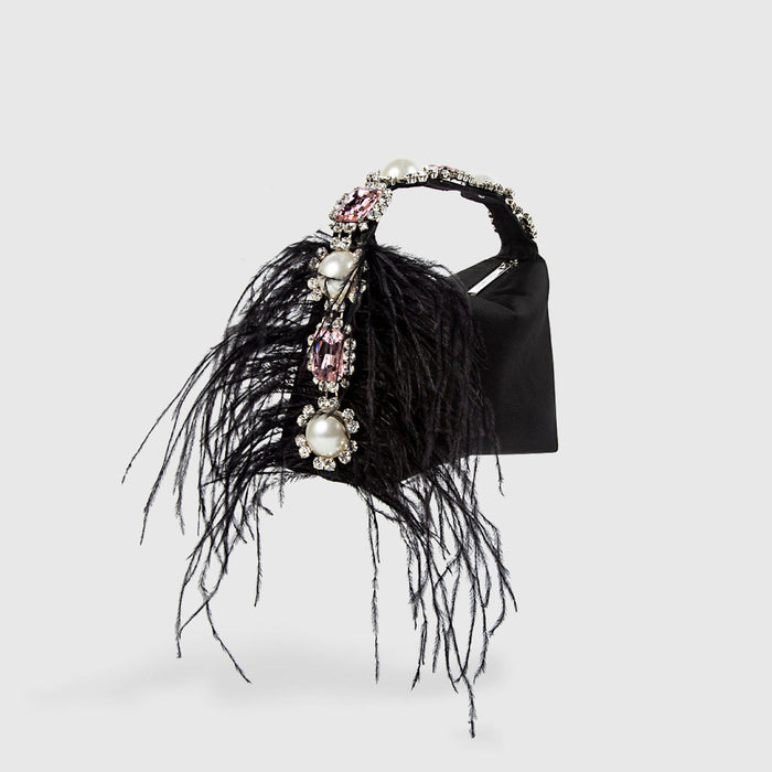 Black handbag with feather detailing and decorative elements on a light gray background