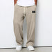 Beige waffle-textured pants with a brand logo worn by a person on a white background