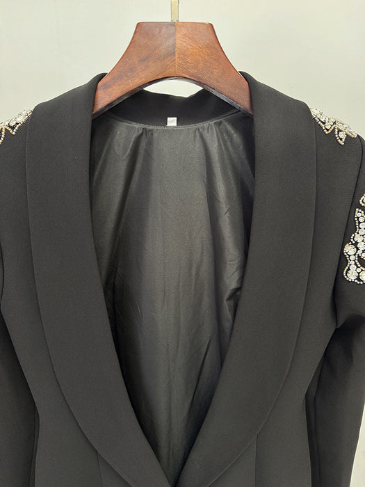 Black blazer with lace detailing on a wooden hanger against a neutral background