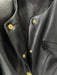 Close-up of a black leather jacket with gold buttons