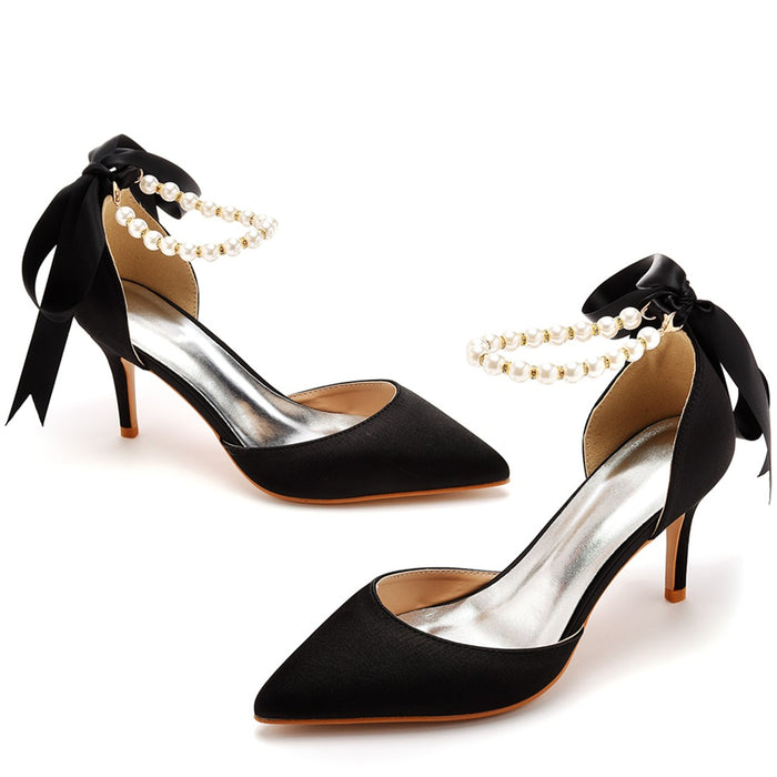 Black high-heeled shoes with pearl anklets on a white background