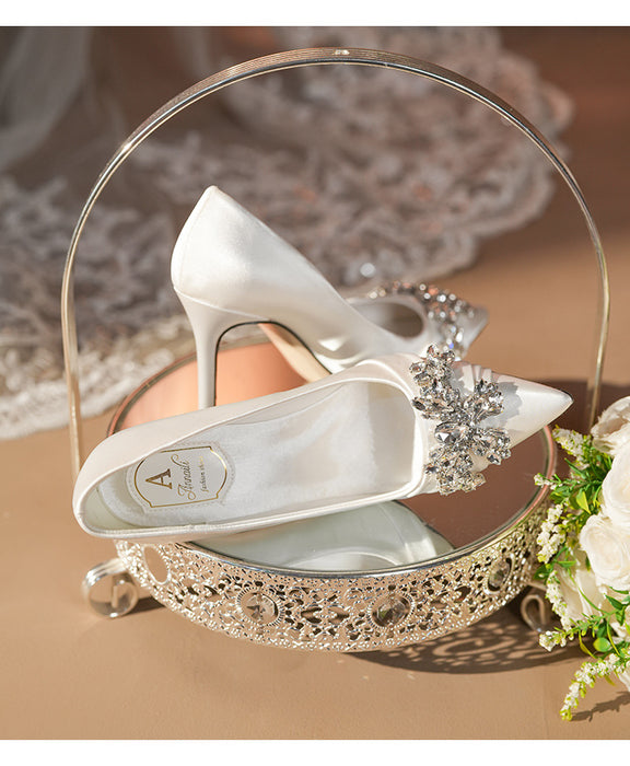 White wedding shoes with a decorative handle and flowers on a brown surface