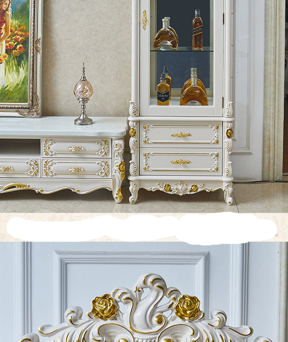 Decorative white cabinet with gold accents and bottles inside, next to a painting on a light-colored wall.