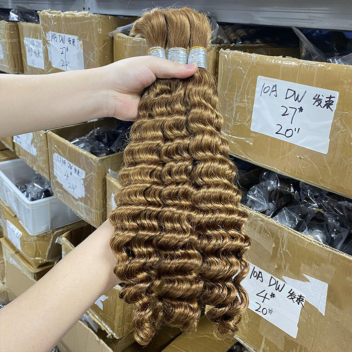 Person holding a bundle of brown hair extensions with boxes in the background