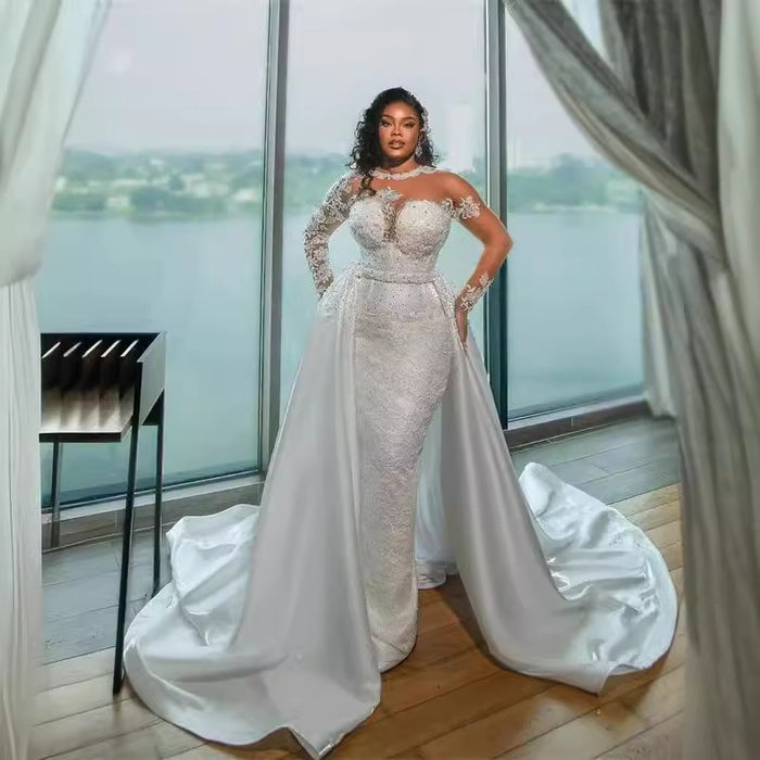 Woman in a white wedding dress standing in a room with large windows.