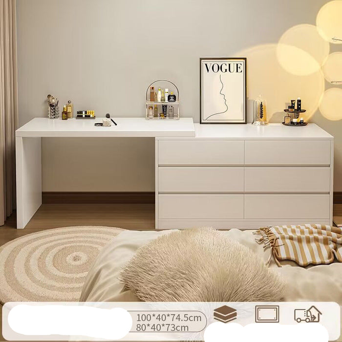 White desk with drawers in a room setting, featuring decor items and a bed.
