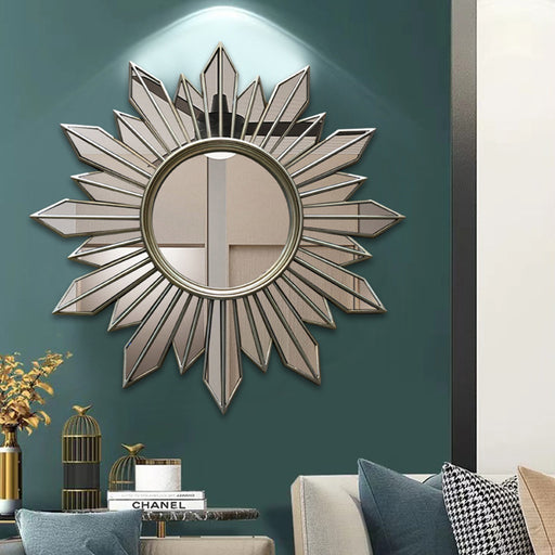 Decorative wall mirror with sunburst design on a teal wall in a living room setting.
