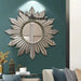 Decorative wall mirror with sunburst design on a teal wall in a living room setting.
