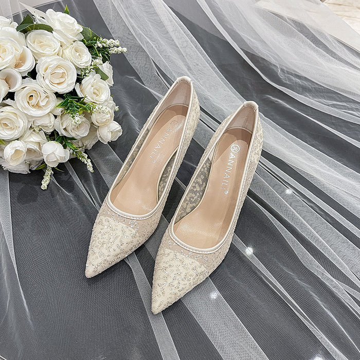 Pair of beige lace shoes with a bouquet of white roses on a gray fabric background