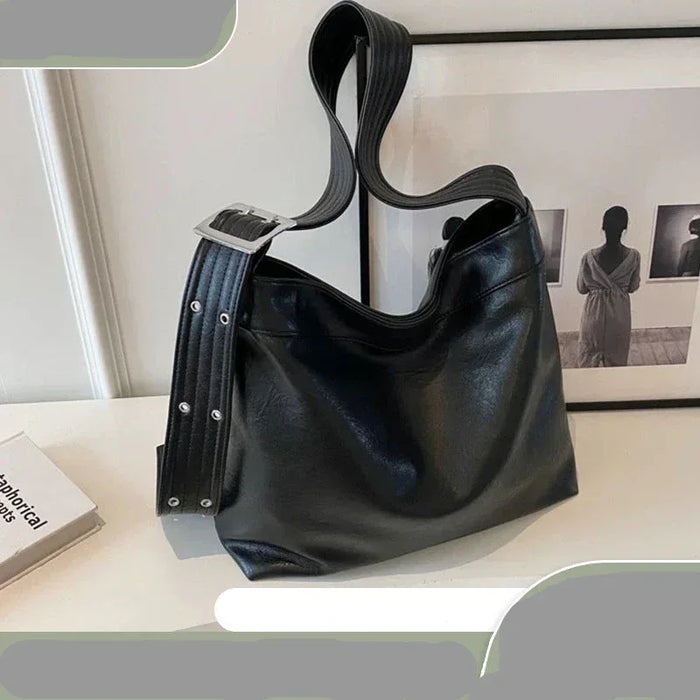 Black handbag on a light surface with a blurred background