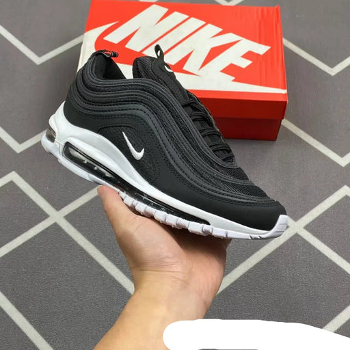 Black Nike sneakers held in a hand with a red Nike box in the background.