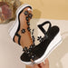 Black and white wedge sandals with floral embellishments on a neutral background