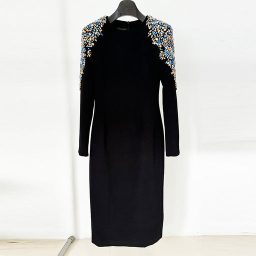 Black dress with embellished shoulders on a hanger against a white background
