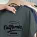 Gray t-shirt with 'California' text on a hanger