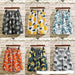 Six pairs of shorts with different patterns hanging against a wooden panel background.