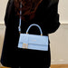 A person wearing a black coat carries a light blue structured handbag with a top handle, gold-tone hardware, and a matching shoulder strap. The bag has a visible Fendi logo on the front flap.