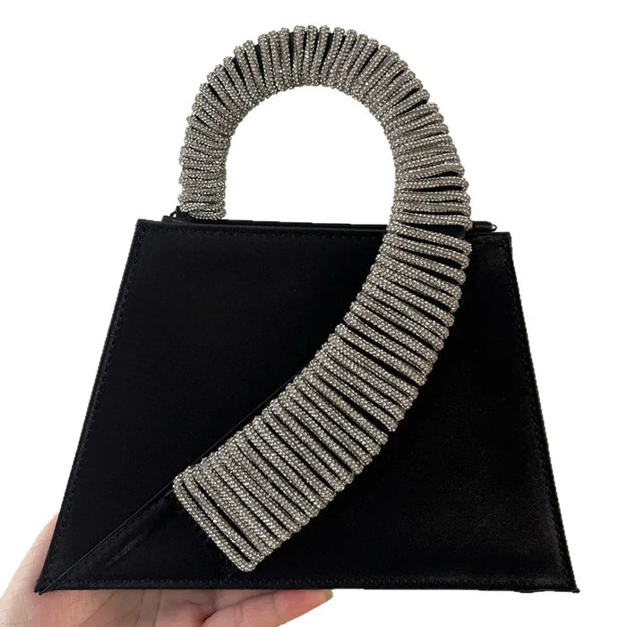 Black handbag with silver beaded handle held by a hand on a white background