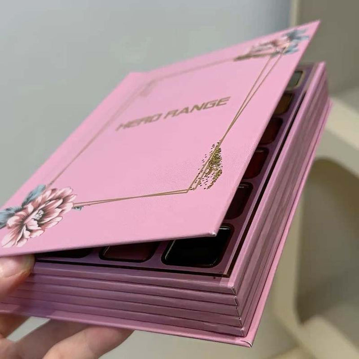 Pink makeup palette with floral designs held by a hand against a neutral background