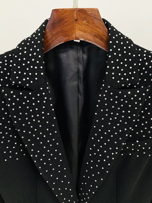 Black blazer with white polka dot pattern on a wooden hanger against a white background