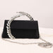 Black handbag with decorative chain handle on a light background