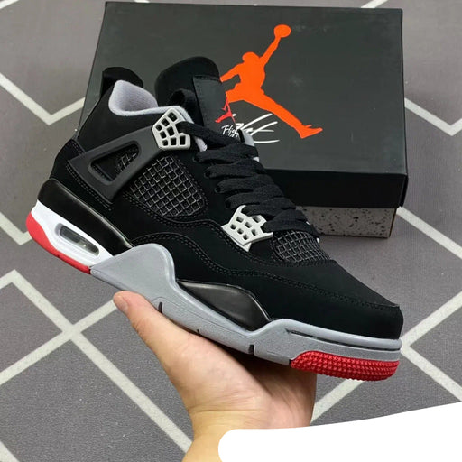 Black and red sneaker held in hand with Jordan brand box in the background