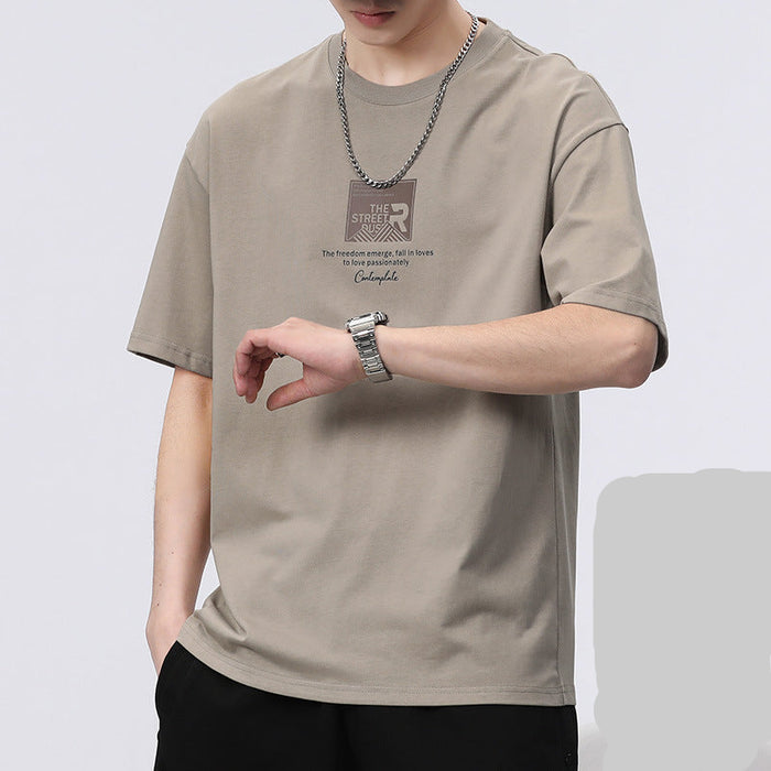 Person wearing a beige t-shirt with text and graphics on a light gray background