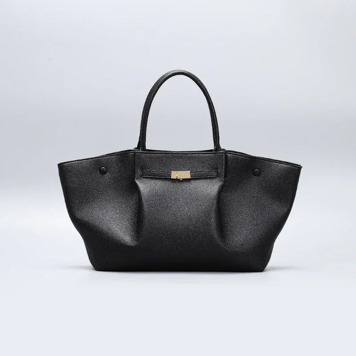 Black handbag with a gold clasp on a light gray background