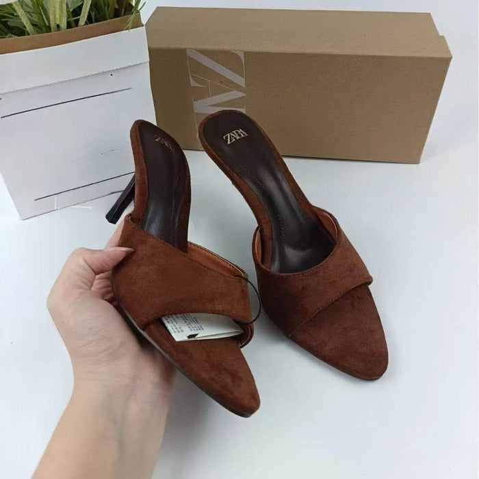 Brown suede high-heeled shoes with a box on a white surface