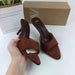 Brown suede high-heeled shoes with a box on a white surface